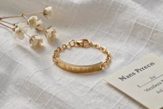 Gourmette bébé en or posée sur un tissu blanc avec des fleurs séchées, cadeau de baptême élégant